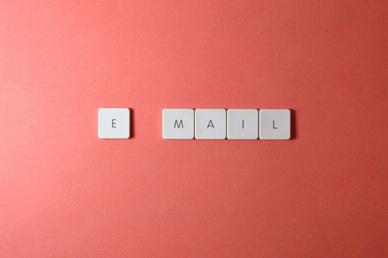 why-choose-us Flat lay of keyboard letter tiles spelling email on coral backdrop.